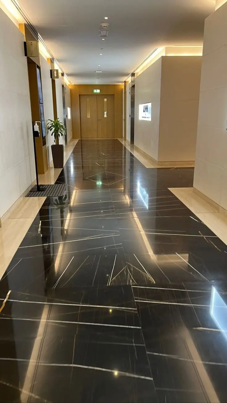 Hall de circulação entregue, com piso de mármore polido, portas de madeira e iluminação embutida.
